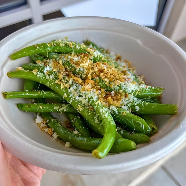 Porano's green beans with crispy garlic and grated cheese in a white bowl.