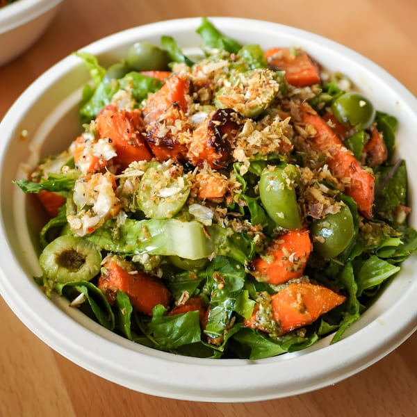 Porano's Italian salad with green lettuce, orange roasted vegetables, green olives, and crunchy toppings.