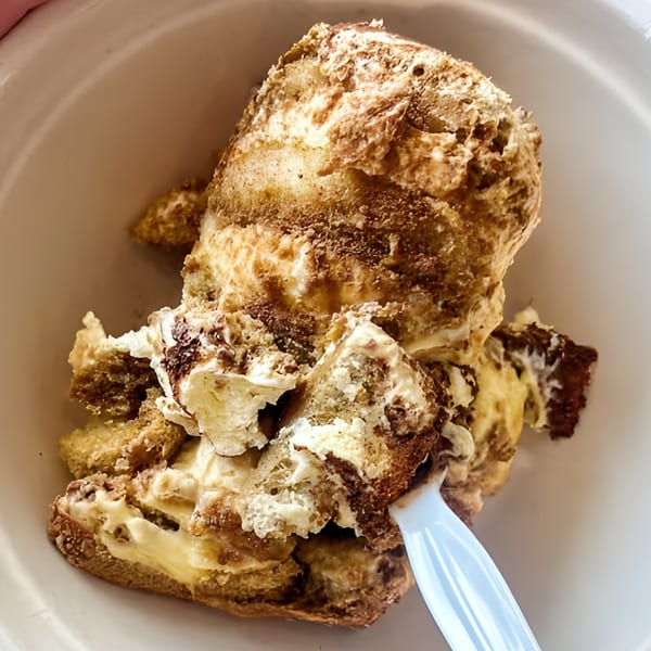 Porano's tiramisu dessert, a creamy, layered Italian classic, served in a white bowl with a spoon.