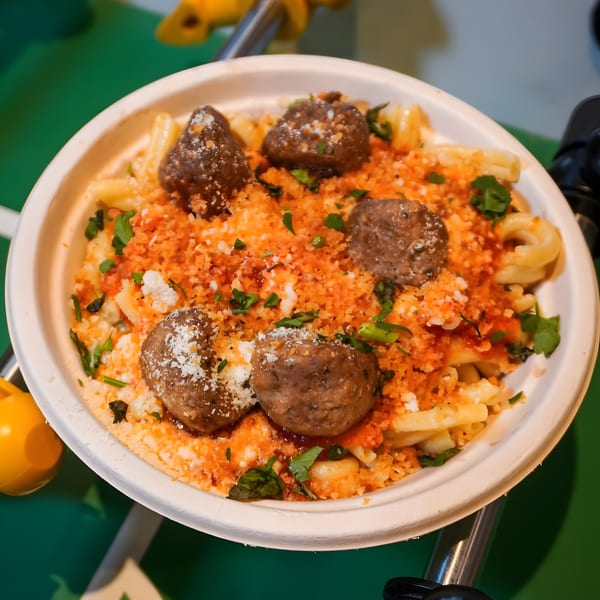 Porano's pasta with meatballs, red sauce, cheese, and herbs in a white bowl.